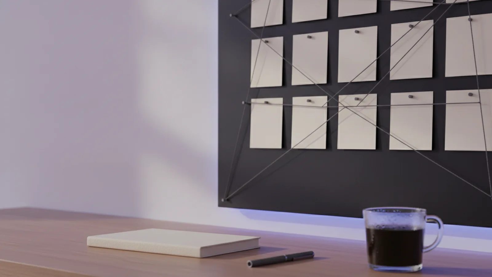 Blank index cards pinned to a dark planning board and linked by taut thread, above a desk with a closed notebook and pen