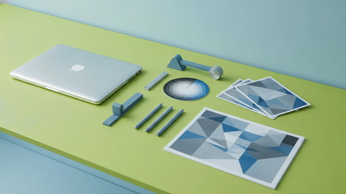 Laptop setup for designing a logo with neatly arranged proof sheets.